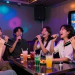 제주유흥을 경험하는 친구들의 즐거운 노래방 시간, 화려한 조명과 음료가 어우러진 생동감 있는 밤.